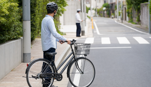 住宅街の横断歩道近くでヘルメットを着けた自転車利用者が安全な距離を取り落ち着いて確認している様子