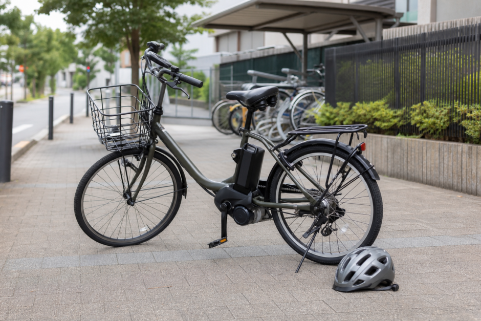 街中に安全に停めた電動アシスト自転車とヘルメット