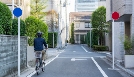 住宅街の一方通行路でヘルメットを着けた自転車利用者が左側を安全に走る様子