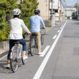 住宅街の道路で前後に並び安全に走る準備をするヘルメット着用の自転車利用者