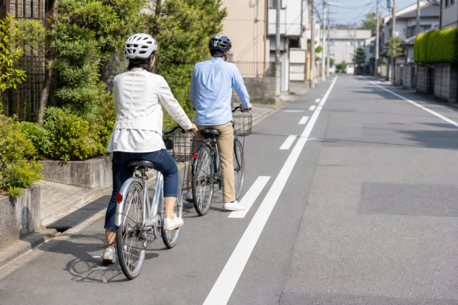 住宅街の道路で前後に並び安全に走る準備をするヘルメット着用の自転車利用者