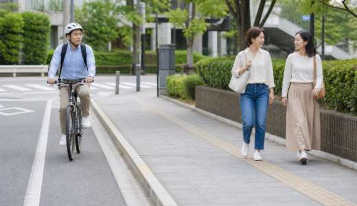 車道側を走るヘルメット着用の自転車利用者と歩道を歩く歩行者が十分な距離を取っている安全啓発イメージ