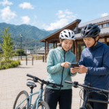 飯山線沿線を走る前に駅前でヘルメットを着用したサイクリストがスマートフォンでルートを確認している様子