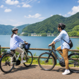 湖畔の道でヘルメットを着用した大人二人がEVアシスト自転車を安全に楽しむイメージ