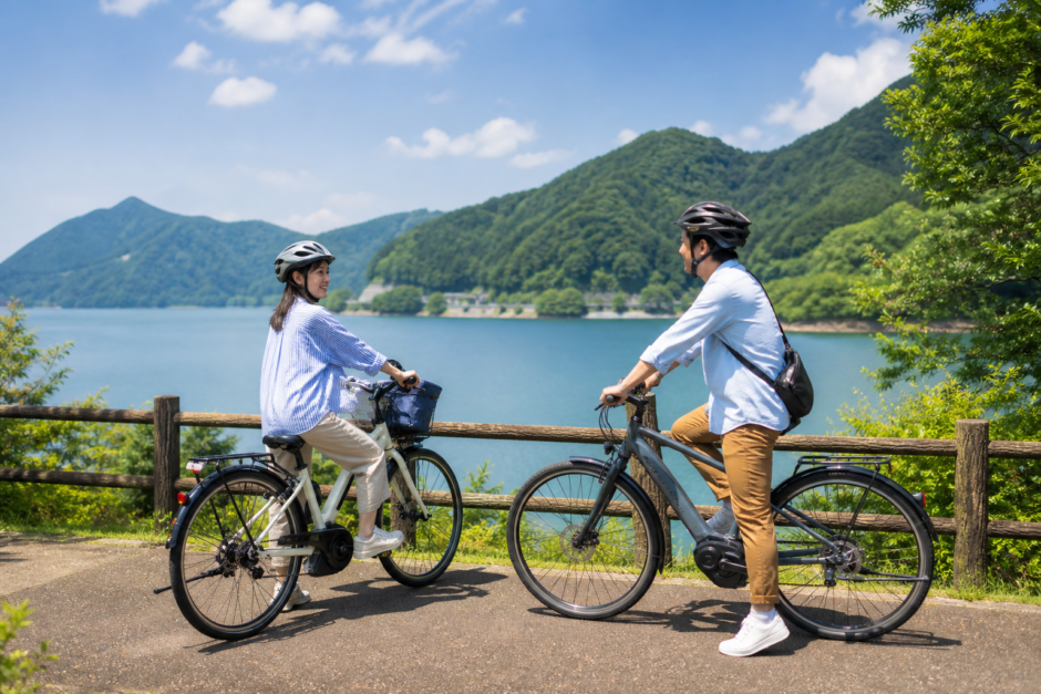 湖畔の道でヘルメットを着用した大人二人がEVアシスト自転車を安全に楽しむイメージ