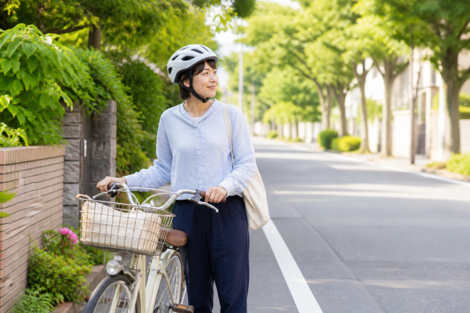夏の街なかで自転車のそばに立つ利用者が一般的な自転車用ヘルメットを正しく着用している様子