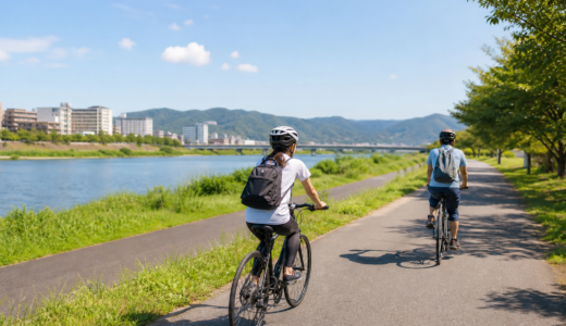 大和川沿いを思わせる明るい河川敷の道をヘルメット姿のサイクリストが安全に走るサイクル月間のイメージ