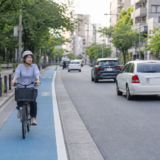 青い自転車レーンを左側通行で安全に走るヘルメット着用の自転車利用者