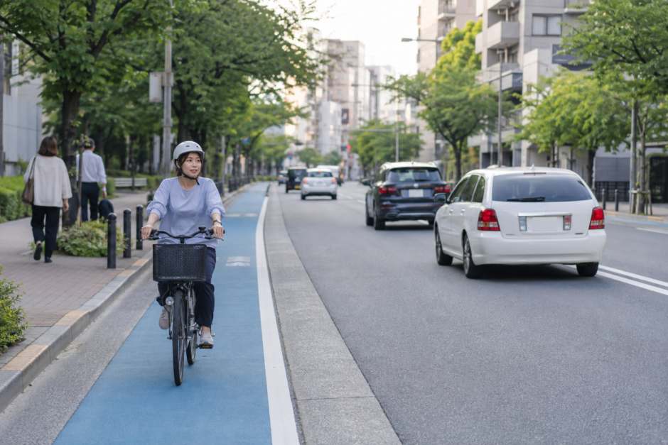 青い自転車レーンを左側通行で安全に走るヘルメット着用の自転車利用者