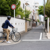 通行規制の標識の手前で止まり安全を確認するヘルメット着用の自転車利用者