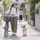 自転車を降りて押しながら歩道で犬のリードを短く持つ利用者