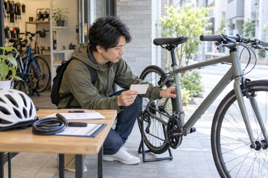 自転車店の前で登録カードと車体番号を確認するヘルメットと鍵を置いた利用者