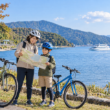 琵琶湖畔でヘルメット姿の親子が自転車を安全に停めて地図を確認している秋の親子サイクリングイメージ